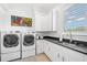 Bright laundry room featuring white cabinets, a black countertop, and modern washer and dryer at 5025 W Homer Ave, Tampa, FL 33629