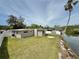 Home exterior with a lush lawn, bay window, white fence, and waterfront views, ideal for serene living at 5043 Osprey Ln, New Port Richey, FL 34652