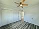 Comfortable bedroom featuring wood-look floors, a ceiling fan, closet, and white walls at 5043 Osprey Ln, New Port Richey, FL 34652