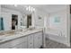Bathroom with double sinks, granite countertops, white cabinets, a large mirror, and a tub at 5938 164Th E Ave, Parrish, FL 34219