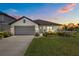 Charming single-story home featuring a well-manicured lawn, gray garage door, and inviting front porch at sunset at 5938 164Th E Ave, Parrish, FL 34219