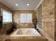 This bathroom features a jacuzzi tub, tile surround, and a glass block window for ample natural light at 6805 Monet Cir, Temple Terrace, FL 33617
