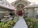 Inviting front entrance with a water fountain, lush garden, and a striking red double-door entry at 6805 Monet Cir, Temple Terrace, FL 33617