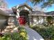 Charming home featuring a lushly landscaped yard, fountain, and striking red door at 6805 Monet Cir, Temple Terrace, FL 33617