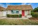 Charming single-story home featuring a red front door, manicured landscaping, and a well-maintained lawn at 6935 Monte Carlo N, Pinellas Park, FL 33781