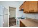 View of kitchen with white appliances, wood cabinets and view into living area at 7051 Dartmouth N Ave, St Petersburg, FL 33710