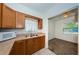 Galley kitchen featuring brown cabinets, stainless steel sink, and floral window curtain at 7051 Dartmouth N Ave, St Petersburg, FL 33710