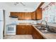 Kitchen with wood cabinets, laminate countertop, double sink and white appliances at 7051 Dartmouth N Ave, St Petersburg, FL 33710