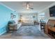 Bright living room with blue accent wall, modern furnishings, hardwood floors, a ceiling fan, and a large window at 8251 Brent St # 941, Port Richey, FL 34668