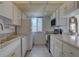 Galley kitchen featuring white cabinets, marble countertops, and stainless steel appliances at 14800 Walsingham Rd # 301, Largo, FL 33774
