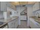 Kitchen with white cabinets, countertop, and view of adjacent dining room and staircase at 14800 Walsingham Rd # 301, Largo, FL 33774