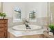 Serene bathroom with a soaking tub, decorative windows with blinds, and neutral tile flooring at 1819 Bella Casa Ct, Tampa, FL 33618