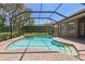 Beautiful screened-in pool with a spa, surrounded by lush landscaping and brick patio at 1819 Bella Casa Ct, Tampa, FL 33618
