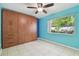 Stylish bedroom featuring built in wall unit, tile floor, ceiling fan, and large window at 23211 Lucerne Pl, Land O Lakes, FL 34639