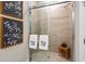 Modern bathroom featuring glass-door shower, neutral tile, and coordinated towels with monogram at 29477 Velletri Ln, Wesley Chapel, FL 33543