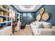 Stylish living room with blue accent wall, decorative wall art, sofa, desk, and shelves at 29477 Velletri Ln, Wesley Chapel, FL 33543