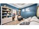 Stylish living room with blue accent wall, decorative wall art, sofa, desk, and shelves at 29477 Velletri Ln, Wesley Chapel, FL 33543