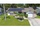 Attractive home featuring solar panels, a green lawn, and palm trees creating a welcoming, energy-efficient facade at 2955 Briar Cliff Dr, Palm Harbor, FL 34684