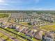 Extensive aerial view of a housing community, highlighting the layout, green spaces, and design of modern homes with solar panels at 4201 Globe Thistle Dr, Tampa, FL 33619
