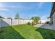 Spacious backyard with green grass, white fence, and a patio area perfect for entertaining at 4201 Globe Thistle Dr, Tampa, FL 33619