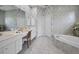 Bright bathroom featuring a vanity with drawers, cabinets, mirror, and a soaking tub at 4693 Aylesford Dr, Palm Harbor, FL 34685