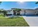 Inviting single-story home with a well-manicured lawn, palm trees, and an attached three-car garage at 4693 Aylesford Dr, Palm Harbor, FL 34685