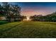 Scenic view of lush green lawn at sunset, framed by mature trees and foliage at 4693 Aylesford Dr, Palm Harbor, FL 34685