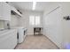 Bright laundry room with white washer and dryer, storage cabinets, and tile flooring at 4693 Aylesford Dr, Palm Harbor, FL 34685