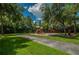 Community playground featuring a colorful play structure, swings, and walking path under a canopy of trees at 4693 Aylesford Dr, Palm Harbor, FL 34685