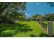 Expansive green yard with a wrought iron fence and mature trees creating a park-like setting at 4693 Aylesford Dr, Palm Harbor, FL 34685