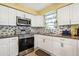Bright kitchen with white cabinets, stainless steel appliances, and updated countertops and backsplash at 500 45Th S St, St Petersburg, FL 33711