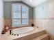 Relaxing bathroom featuring a soaking tub under a bright window with privacy shutters at 5623 Jobeth Dr, New Port Richey, FL 34652