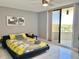 Bright bedroom featuring tile floors, ceiling fan, balcony access, and an inviting yellow floral comforter at 5940 Pelican Bay S Plz # 1105, Gulfport, FL 33707