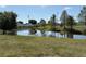 Scenic view of a pond surrounded by trees, lush green grass, and a white vinyl fence in the background at 6221 13Th N Ave, St Petersburg, FL 33710