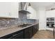 Close up of the gourmet kitchen with stone backsplash, black cabinets, stainless appliances, and gas stove at 6313 Brevada Ln, Apollo Beach, FL 33572