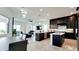 Modern kitchen with dark cabinetry, pendant lighting, and stainless steel appliances, seamlessly flowing into the living area at 684 Regatta Way, Bradenton, FL 34208