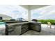 This outdoor kitchen features stone accents, stainless steel appliances, and counter seating with beautiful outdoor views at 684 Regatta Way, Bradenton, FL 34208