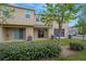 The back of the beige home has lush grass, landscaping, and a covered patio at 7029 White Treetop Pl, Riverview, FL 33578