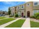View of townhome exteriors with landscaped lawns and sidewalks, under a clear blue sky at 7029 White Treetop Pl, Riverview, FL 33578