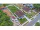 Aerial view features a light-blue home, brown roof, white fence, ample parking, and a well-manicured lawn at 8505 N Brooks St, Tampa, FL 33604
