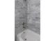 Modern bathroom featuring gray tiled walls, glass shelving, and a soaking tub at 8505 N Brooks St, Tampa, FL 33604