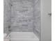 Modern bathroom with marble-style tile, bathtub, and white fixtures at 8505 N Brooks St, Tampa, FL 33604