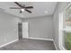 Bright bedroom with gray wood-look floors, a ceiling fan, and a view of the backyard at 8505 N Brooks St, Tampa, FL 33604