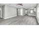 Spacious living room with gray wood-look floors, ceiling fan, and a view into the modern kitchen at 8505 N Brooks St, Tampa, FL 33604