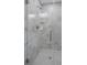 New shower with glass doors, marble-patterned tile, glass shelves, and chrome fixtures at 8505 N Brooks St, Tampa, FL 33604