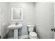 Downstairs bathroom with pedestal sink, modern toilet, and gray plank flooring at 8818 Poe Dr, Hudson, FL 34667