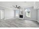 Open-concept living room featuring hardwood floors, a fireplace, a ceiling fan, and natural light at 8818 Poe Dr, Hudson, FL 34667
