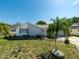 Landscaped front yard with a young palm tree and gray decorative rock leading to the cozy single-story home at 12202 Meadowbrook Ln, Hudson, FL 34667