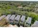 Aerial view of multiple two-story homes with trees surrounding the neighborhood showcasing the neighborhood and the surrounding landscape at 1353 Curlew Rd, Dunedin, FL 34698