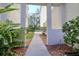 A covered walkway through tropical plants leads to the green lawn and seating beyond at 1353 Curlew Rd, Dunedin, FL 34698